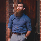 Savage Gentleman "Everyman Shirt" in blue. Man leaning against brick building.