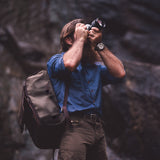 Man taking pictures with. a camera bag over the shoulder.