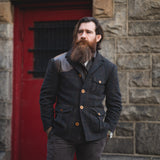 Rugged men's fashion for the Savage Gentleman. Man standing in front of red door.