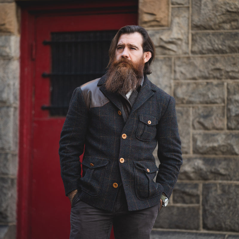 Rugged men's fashion for the Savage Gentleman. Man standing in front of red door. 