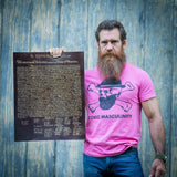 Josh Tyler MMA hält die Unabhängigkeitserklärung aus dunkelbraunem Leder vor einer alten Scheune und trägt ein rosafarbenes Toxic-Masculinity-T-Shirt