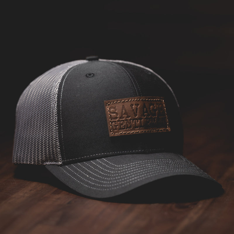 Savage Gentleman Leather Patch Trucker Hat in grey mesh and black.